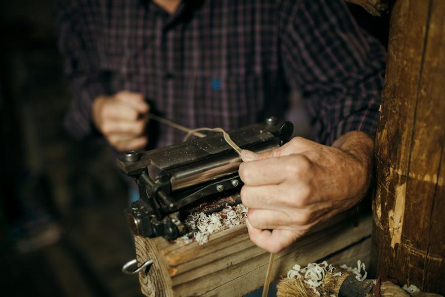 Hands re-stitching leather at a workbench